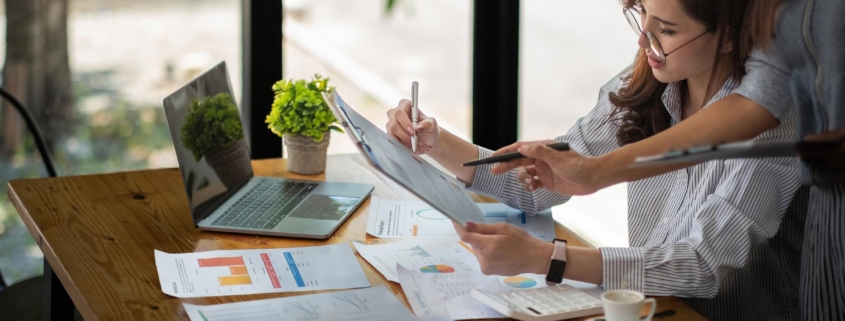 Two business partnership coworkers discussing a financial planning graph and company during a budget meeting in office room.