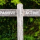 Wooden signpost with two opposite arrows over green leaves background. Passive versus Active directional signs, Choice concept image