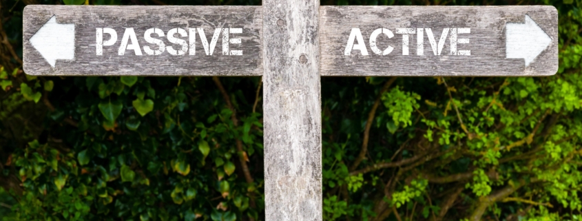 Wooden signpost with two opposite arrows over green leaves background. Passive versus Active directional signs, Choice concept image