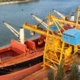 Crane unloads iron ore at the harbor. Trade in raw materials. Work at a port in the Baltic Sea