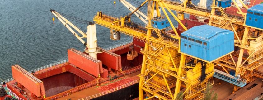 Crane unloads iron ore at the harbor. Trade in raw materials. Work at a port in the Baltic Sea