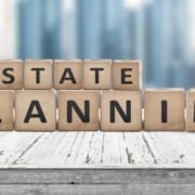 Estate planning sign on a wooden pier with tall buildings in the background