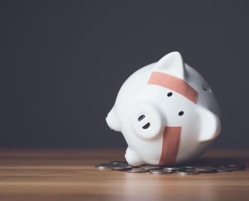 Financial problem, Bankrupt or fail in business concept. White piggy bank with plastic adhesive bandages on wooden desk with dark copy space wall background. Fail, Bankrupt or unsuccessful idea.