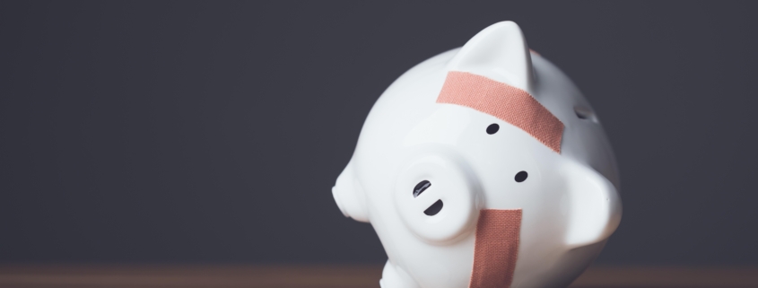 Financial problem, Bankrupt or fail in business concept. White piggy bank with plastic adhesive bandages on wooden desk with dark copy space wall background. Fail, Bankrupt or unsuccessful idea.