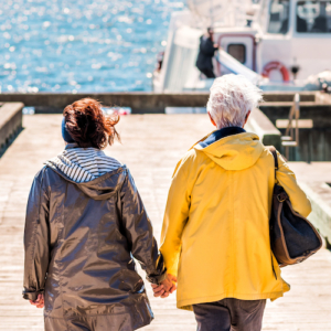 Perce: Bonaventure Island Park entrance in Gaspe Peninsula, Quebec, Gaspesie region with senior couple woman holding hands walking to boat ferry on dock pier