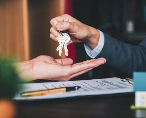 estate agent giving house keys to woman and sign agreement in office