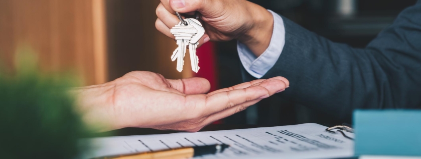 estate agent giving house keys to woman and sign agreement in office