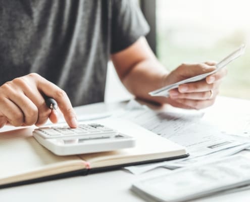 Man using calculator Accounting Calculating Cost Economic bills with money stack step growing growth saving money in home , finance concept