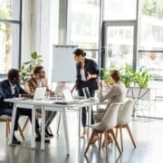 multiethnic businesspeople at table with laptops during conference in office