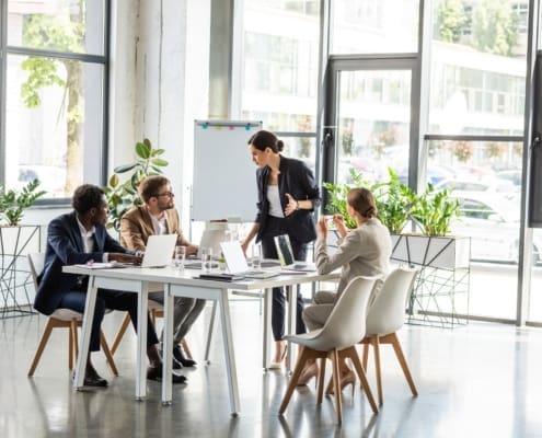 multiethnic businesspeople at table with laptops during conference in office
