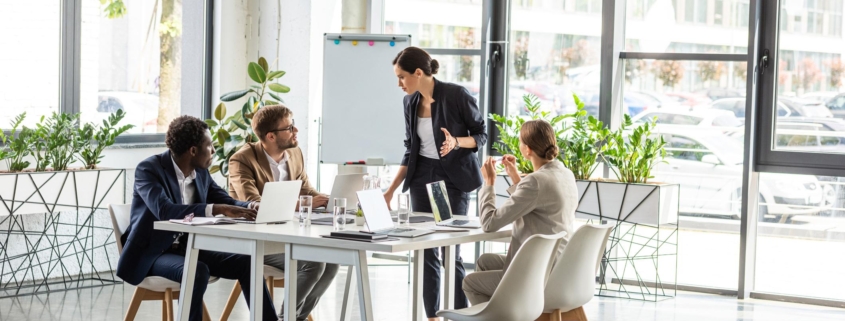 multiethnic businesspeople at table with laptops during conference in office