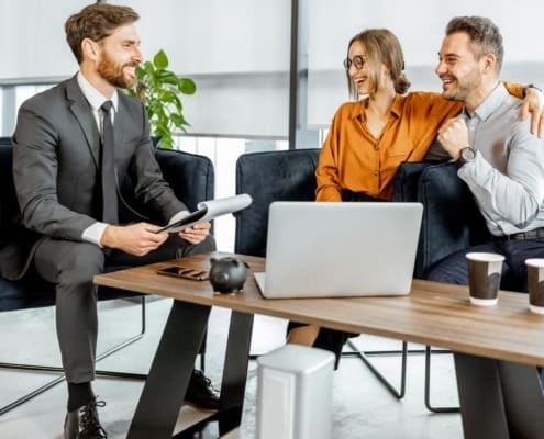 Happy young couple having a great deal with financial advisor or real estate agent at the luxury office. Investment, lending or or successful resolution of legal issues for a young family