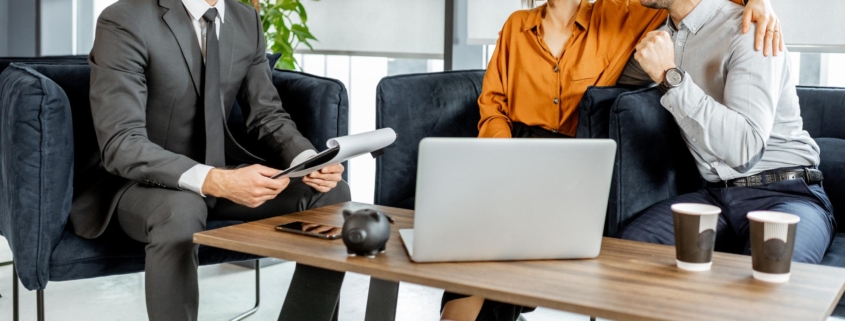 Happy young couple having a great deal with financial advisor or real estate agent at the luxury office. Investment, lending or or successful resolution of legal issues for a young family