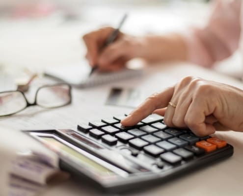Pension calculation concept, old hands counting finances on a home calculator ,