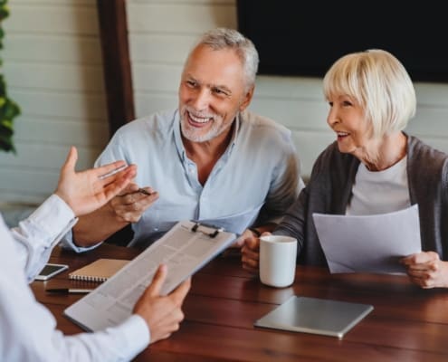 Happy aged couple consulting with insurance agent at home