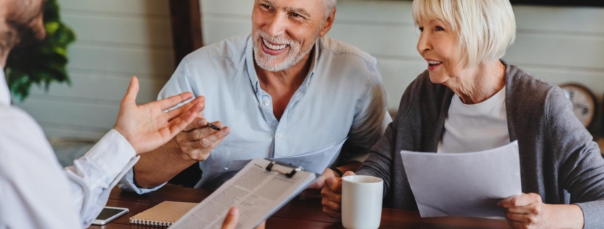 Happy aged couple consulting with insurance agent at home