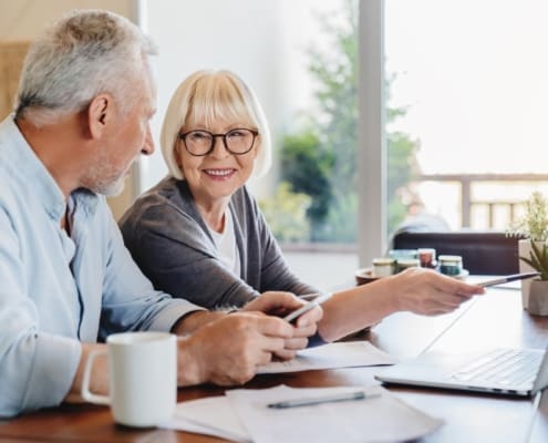 Senior couple doing home finances using laptop indoors
