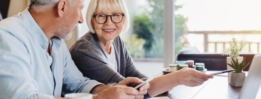 Senior couple doing home finances using laptop indoors