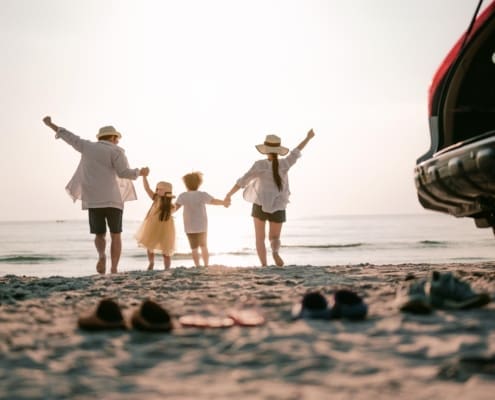 Family vacation holiday, Happy family running on the beach in the sunset. Back view of a happy family on a tropical beach and a car on the side.