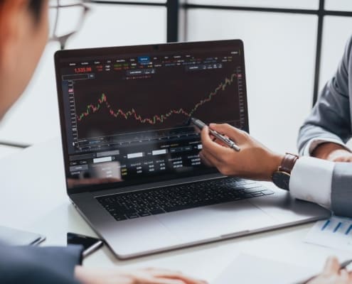 Businessman talking about investment stock market and graph from computer laptop with broker trader, giving money plan management and analysis. Depicts TradingView financial market chart.