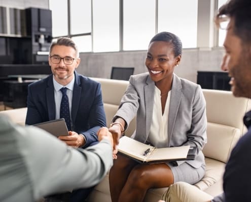 Smiling mature black businesswoman shaking hand with new client in modern office. Successful african american woman manager shaking hands with executive during business meeting. Professional ceo signing a deal with handshake with new partner.
