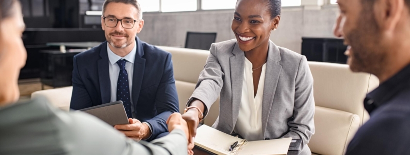 Smiling mature black businesswoman shaking hand with new client in modern office. Successful african american woman manager shaking hands with executive during business meeting. Professional ceo signing a deal with handshake with new partner.