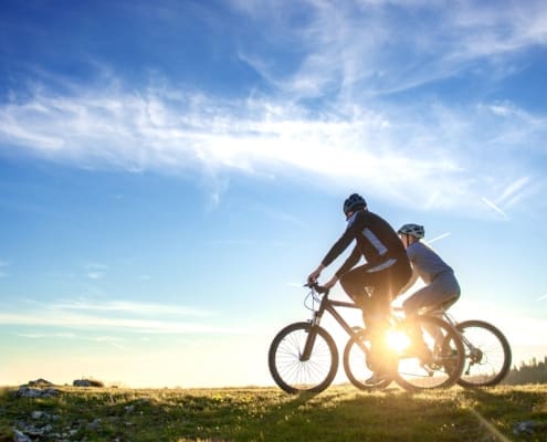 Happy mountain bike couple outdoors have fun together on a summer afternoon sunset.