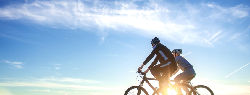 Happy mountain bike couple outdoors have fun together on a summer afternoon sunset.