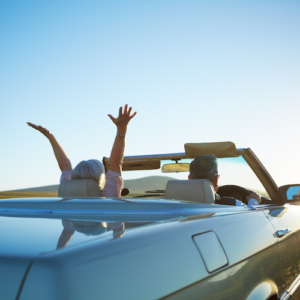 Rear view shot of a mature woman raising her hands in excitement for the roadtrip she is going on with her husband