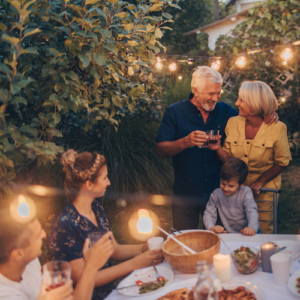 Photo of a senior couple, celebrating their anniversary with family, having a dinner outdoors in the back yard